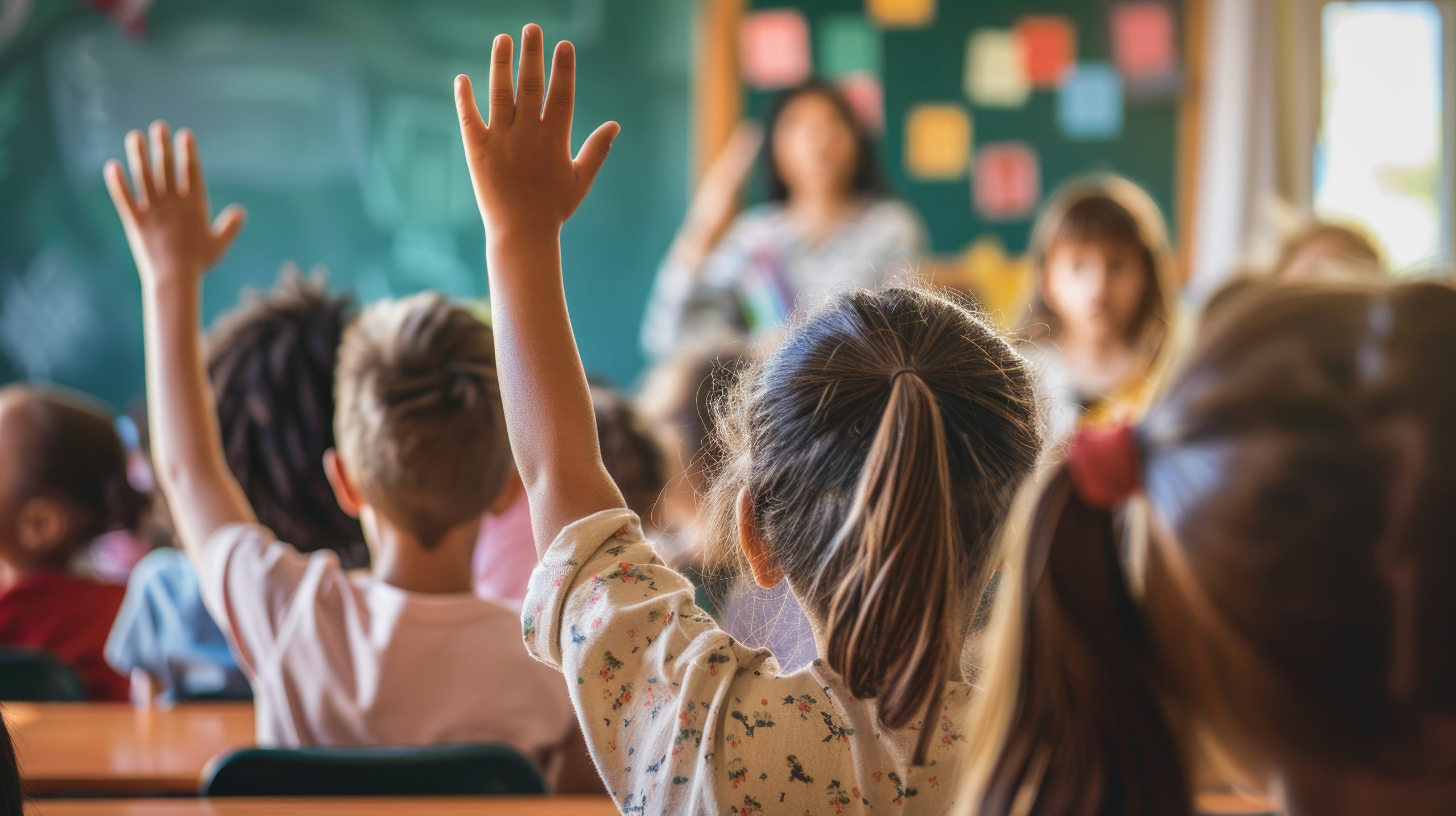 School kids raising hand in classroom at elementary school.
